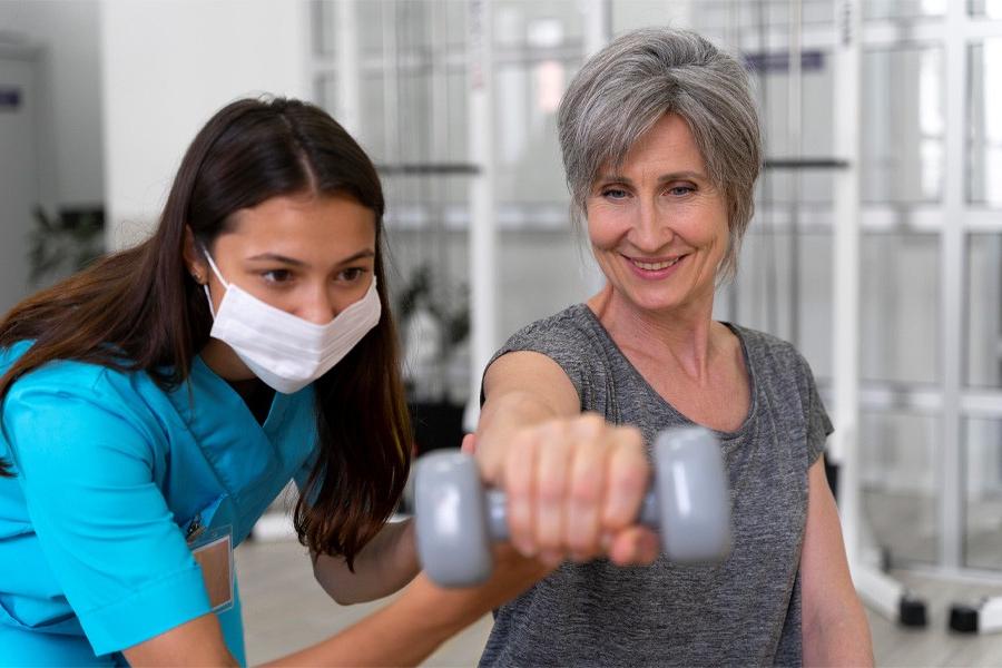 Woman lifting weight with assistance from medical professional